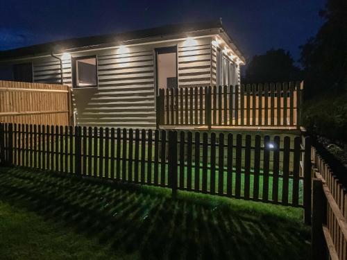 a fence in front of a house with lights at Lodge With A View in Steyning