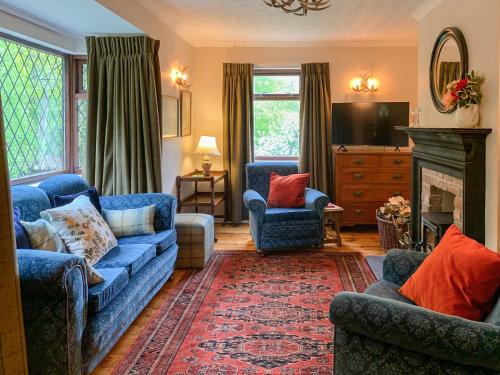 a living room with blue couches and a fireplace at Forester's Cottage in Kildary