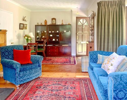 a living room with two blue chairs and a red pillow at Forester's Cottage in Kildary