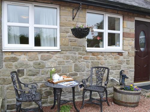 two chairs and a table in front of a stone house at The Gin Gan Cottage in Ryal