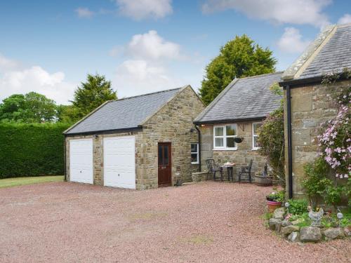 a stone house with two garage doors in a driveway at The Gin Gan Cottage in Ryal