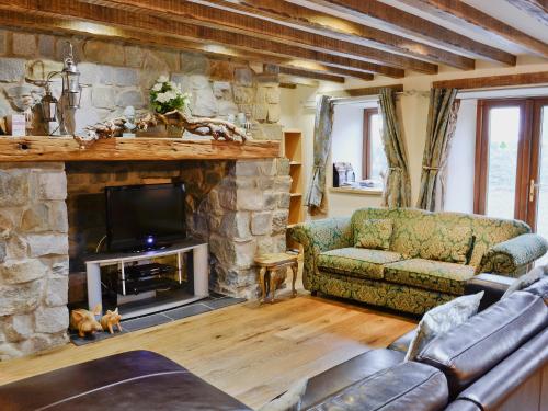 a living room with a couch and a stone fireplace at Kris Kin in Criccieth