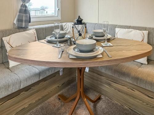a wooden table with plates and wine glasses on it at Kjs Holiday Haven in Ayr