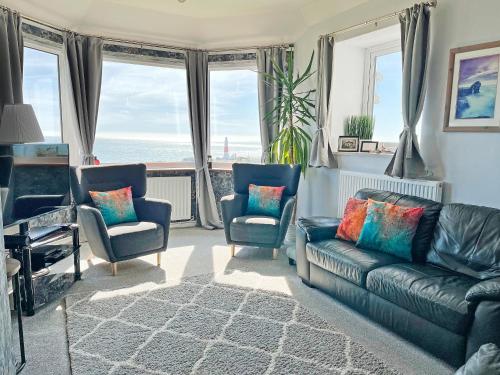 a living room with a couch and chairs and the ocean at Lloyds Cottage in Southwell