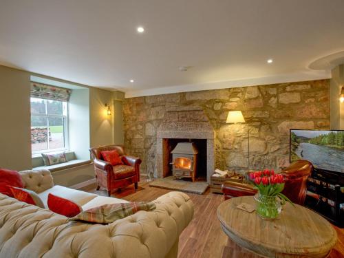 a living room with a couch and a fireplace at Potarch Lodge in Kincardine OʼNeil
