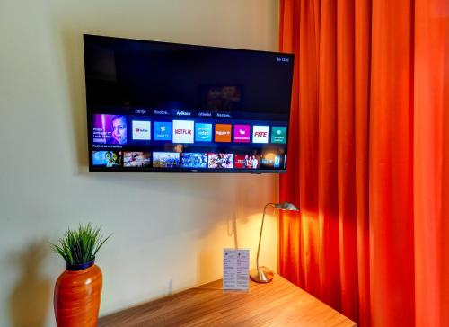 a flat screen tv on a wall with an orange curtain at Hotel Hermes in Krnov