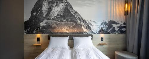 two beds in a hotel room with a painting on the wall at Zleep Hotel Lausanne-Chavannes in Lausanne