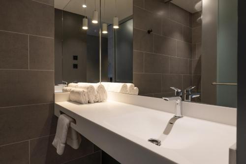 a bathroom with a sink with a mirror and towels at Zleep Hotel Lausanne-Chavannes in Lausanne