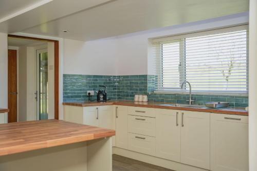 a kitchen with white cabinets and a sink and a window at Ceunant in Llanfair Caereinion