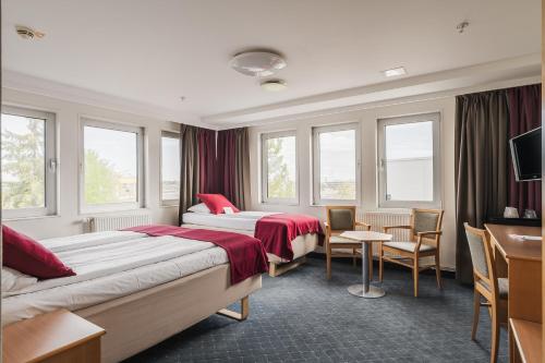ein Hotelzimmer mit zwei Betten, einem Tisch und Stühlen in der Unterkunft 2Home Stockholm South in Stockholm