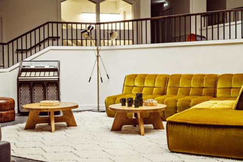 a living room with a yellow couch and two tables at Le Val Thorens, a Beaumier hotel in Val Thorens
