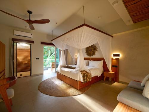 a bedroom with a canopy bed with a ceiling at Samawa Living in Paje