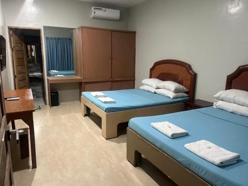 a room with two beds and a cabinet in it at B&S Pension House in Dipolog