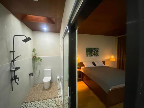 a small bedroom with a bed and a bathroom at Tropical Aurora Tetebatu in Tetebatu