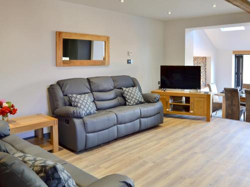 a living room with a couch and a flat screen tv at Jupiter Barn in Swafield