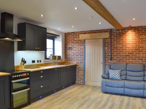 a kitchen with a blue couch and a brick wall at Jupiter Barn in Swafield