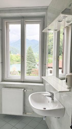 a white bathroom with a sink and two windows at Hotel Lucija in Most na Soči