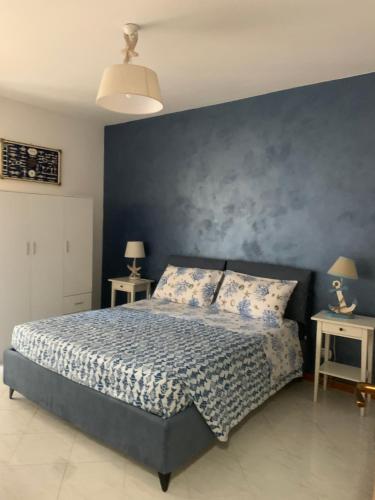 a bedroom with a bed with a blue wall at A due passi dal mare 2023 in Nettuno