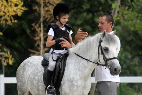 a young child riding on a white horse with a man at Boutique Complex Trakiets in Zhitnitsa
