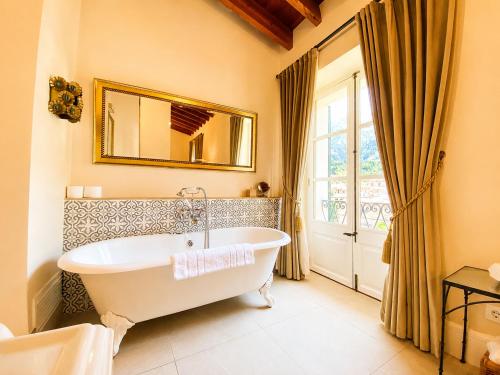 een badkamer met een badkuip, een spiegel en een raam bij The Salvia - Adults Only in Sóller