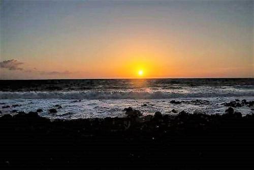 a sunset on a beach with the ocean at Sea Breeze Apartment in Korakokhórion