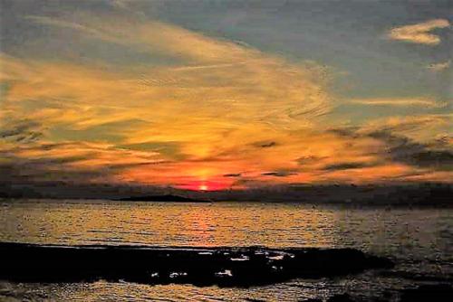 a sunset over a body of water with the ocean at Sea Breeze Apartment in Korakokhórion