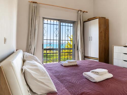 a bedroom with a purple bed with towels on it at Villa LaThea in Akti Salonikiou