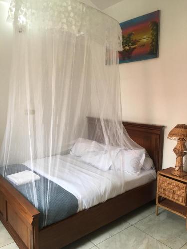 a bedroom with a canopy bed with white sheets and pillows at Meublé de toursime L'Escale in Yaoundé