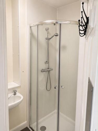 a shower with a glass door and a sink at Morlich Guesthouse in Dingwall