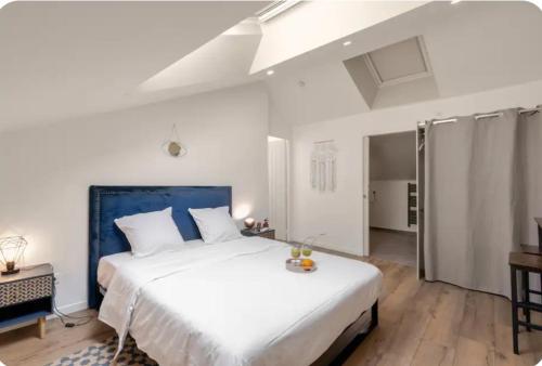 a bedroom with a large white bed with a blue headboard at Chambre Attrape rêves in Sainte-Geneviève-des-Bois