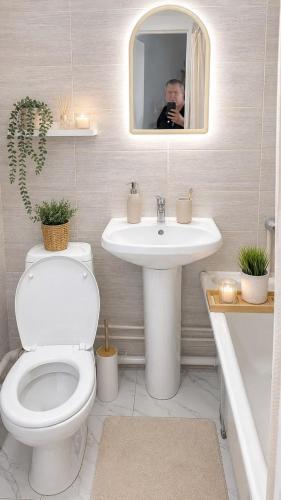 a man taking a picture of a bathroom with a toilet and sink at квартира жубанова in Aktobe