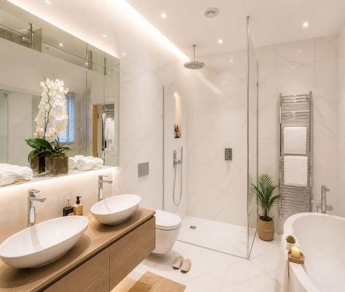 a white bathroom with two sinks and a shower at Hotel GRAN-SOL Near DELHI Airport in New Delhi