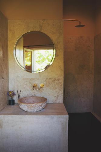 a bathroom with a large stone sink with a mirror at LE CLOS DES ARÔMES in Cassis
