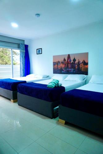 three beds in a room with blue lighting at Hospedaje Parque Central frente al parque principal in Santa Rosa de Cabal