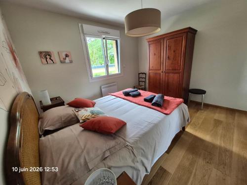 a bedroom with a bed with red pillows and a window at Chambres d'hotes PROCHE CIRCUIT in Arnage