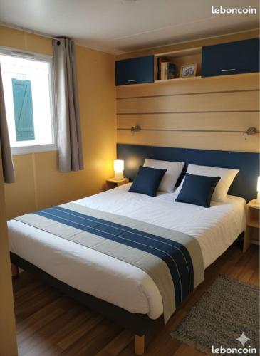 a large bed with blue pillows in a bedroom at camping du Coucou in Nailhac