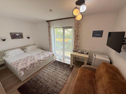 a bedroom with a bed and a couch and a window at Pensiunea Indra in Gura Humorului