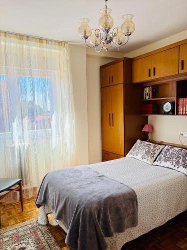 a bedroom with a bed and a chandelier at Piso céntrico y luminoso in León