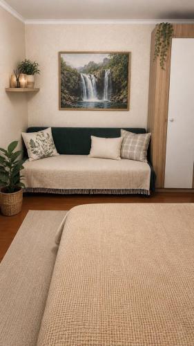 a living room with a couch and a painting of a waterfall at квартира жубанова in Aktobe