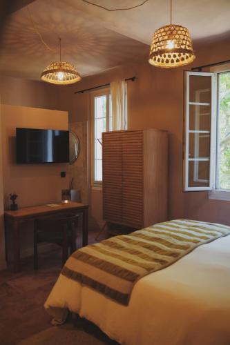 a bedroom with a bed and a desk and two lights at LE CLOS DES ARÔMES in Cassis