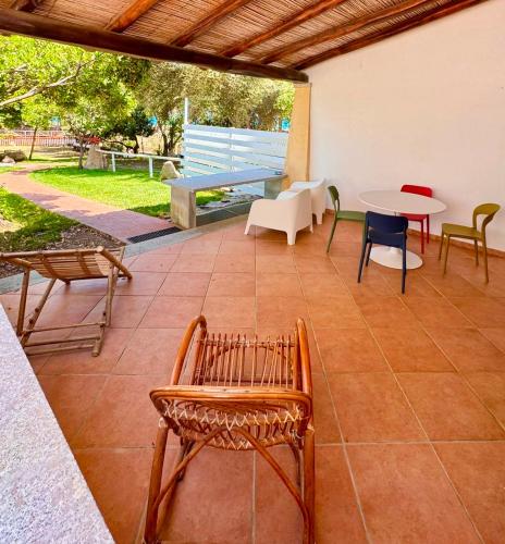 a patio with chairs and a table and a bench at Le Corti Sarde On The Beach in Bari Sardo