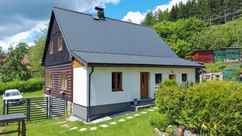 a small house with a black roof at Chalupa Emma in Tanvald