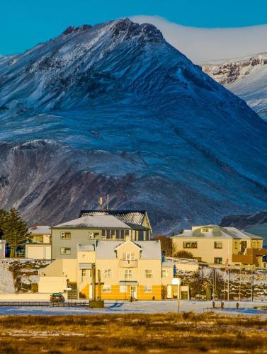 a large building with a mountain in the background at Hvammur Apartments by the Harbour in Höfn