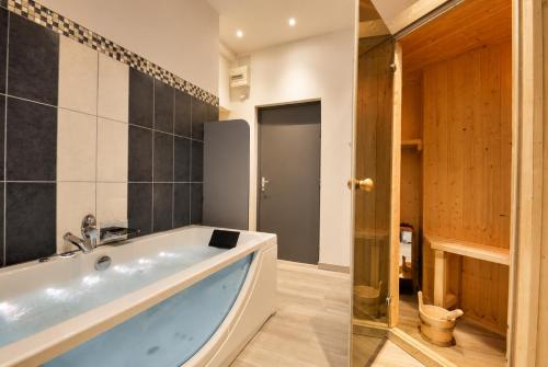 a bathroom with a large tub in a room at Sous le Charme de Charles Sauna & Jacuzzi Nancy in Nancy
