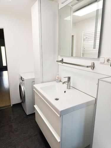 a white bathroom with a sink and a mirror at Ferienhaus-Kassiopeia in Laboe