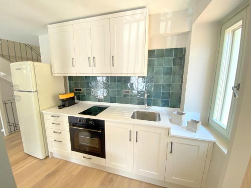a kitchen with white cabinets and a sink and a refrigerator at Metropolis Nextdoor in Vathi