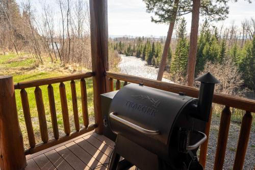 a grill on a porch with a view of a river at Glacier River Ranch - South Fork in Columbia Falls