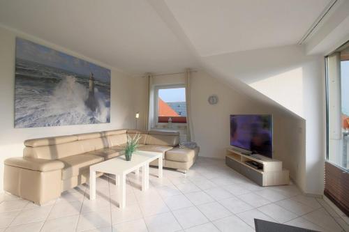 a living room with a couch and a tv at FW2 Deichperle in Wremen