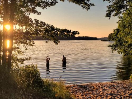 two people are standing in a lake at sunset at Dom Widny Jaś zaprasza nad jezioro na Kaszuby in Sulęczyno
