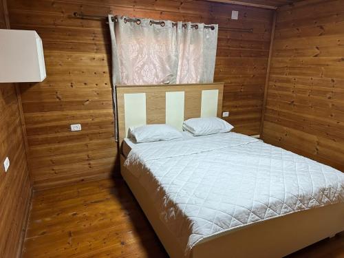 a bed in a room with wooden walls and a window at carmel cabins suite 6 in Yājur